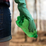 Eine junge Frau sammelt Plastikmüll in einer Grünanlage.