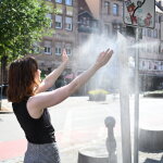 Eine Frau kühlt sich unter dem kühlen Wassernebel einer Sprühnebelsäule.