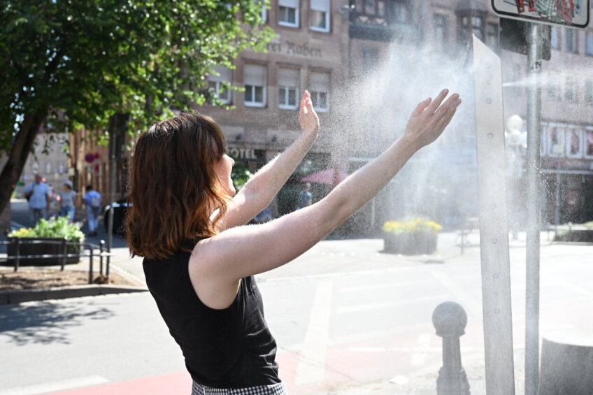 Eine Frau kühlt sich unter dem kühlen Wassernebel einer Sprühnebelsäule.
