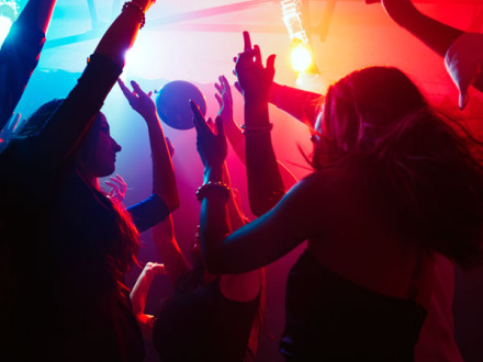 Das Bild zeigt: Junge Leute tanzen in einer Disco.