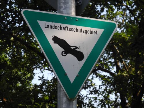 Ein Schild mit einem Adler auf weißem Grund weist ein Landschaftsschutzgebiet aus.