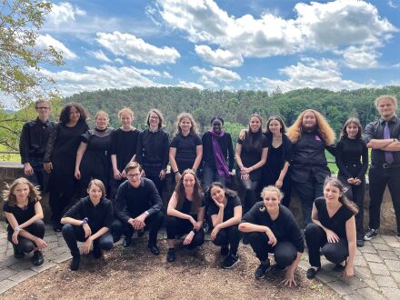 Foto von den Mitgliedern vom Jungen Chor von der Musik·schule Nürnberg. Alle Personen haben schwarze Kleidung an. Die Personen in der hinteren Reihe stehen. Die Personen in der vorderen Reihe hocken., Bild © Manuel Krauss