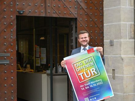 Das Bild zeigt den Ober·bürgermeister Marcus König mit einem Plakat zum Tag der offenen Tür im Jahr 2022.