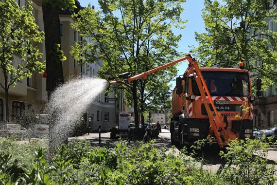 Ein modernes Bewässerungsfahrzeug des Servicebetriebs Öffentlicher Raum Nürnberg gießt einen Baum in der Nürnberger Südstadt