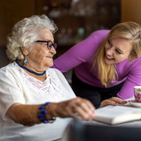 Eine Seniorin wird in ihrem Zuhause von einer jungen Frau betreut.