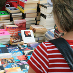 Eine frau stöbert auf einem Bücher-Flohmarkt.