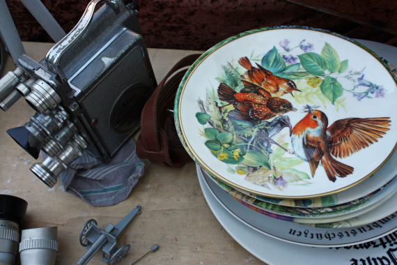 Eine alte Filmkamera und Teller auf einem Verkaufstisch auf dem Trempelmarkt.