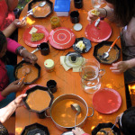Menschen essen gemeinsam Suppe an einem gedeckten Tisch.