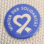 Button mit dem Logo des Winters der Solidarität auf weißem Pullover.