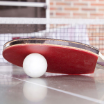 Tischtennisschläfer- und -Ball auf einer Platte.