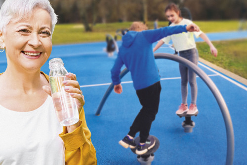 Frau trinkt Wasser und Jugendliche trainieren im Bewegungspark.