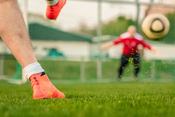 Schuhe eines Fußballspielers, der gerade den Ball ins Tor schie