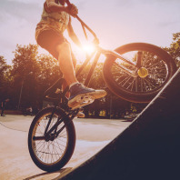 Ein Junge fährt in einem Skatepark mit einem BMX-Fahrrad eine Rampe hoch.