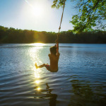Ein Junge macht einen Bungee Jump in einen Badesee.