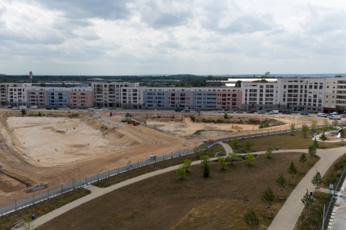Das neue Quartier Lichtenreuth: Im Hintergrund befinden sich die bereits errichteten Wohnungen des ersten Bauabschnitts. In der Mitte des Bildes befindet sich die Baufläche für die weiteren Bauabschnitte. Im Vordergrund ist die Rasenfläche des im Jahr 2025 fertiggestellten nördlichen Teils des neuen Quartierparks zu sehen.