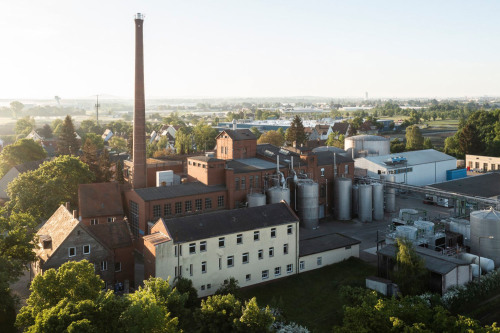 Visualisierung des ehemaligen Hefewerks „Beim Bast“ in Buch Süd: Blick auf das Gelände und die Anlagen aus der Vogelperspektive. Rund um das Gelände soll ein neues Wohnquartier entstehen. Das Areal am ehemaligen Hefewerk wird zur „neuen Mitte beim Bast“. Gastronomie sowie kulturelle Angebote laden zum Austausch und zur Begegnung ein.