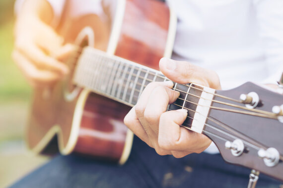 Ein Mann spielt sitzend Gitarre.