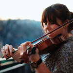 Eine junge Frau spielt im Freien Geige.