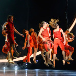 Ensemble des Staatstheaters Nürnberg in roter Kleidung auf der Bühne.