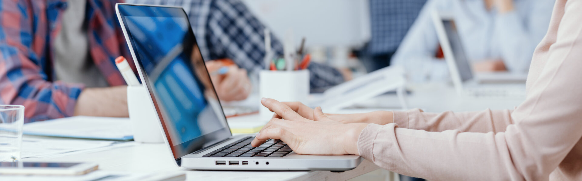 Young business team meeting in the office and working, a woman is using a laptop on the foreground: start up and innovation concept