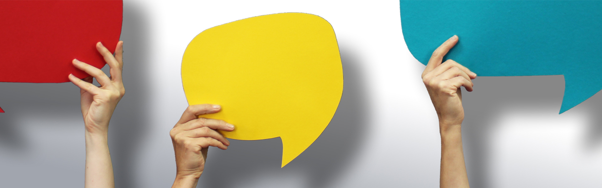 Bunte Sprechblasen von Händen hochgehalten