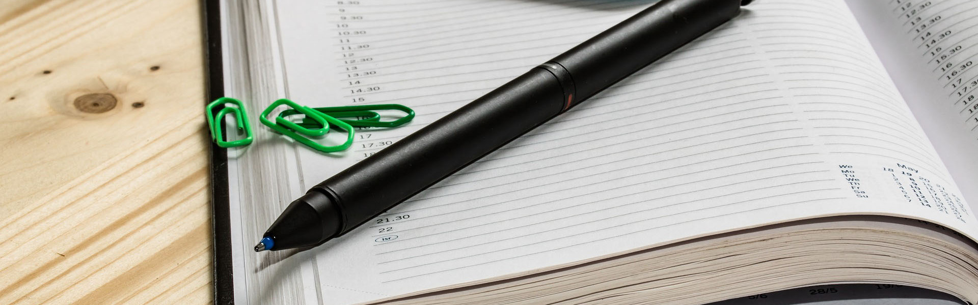 offener Terminkalender mit Stift, Büroklammern und Handy