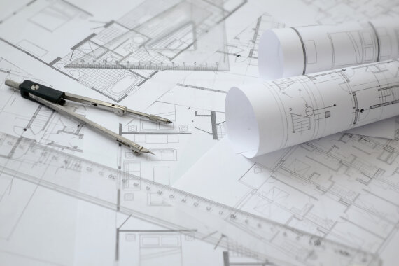 Foto von Bau·plänen und einem Zirkel und einem Lineal.