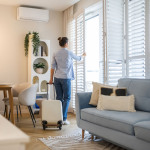 Eine Frau ist gerade in einer Ferienwohnung angekommen. Im Vordergrund steht ihr noch nicht ausgepackter Koffer.