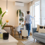 Eine Frau ist gerade in einer Ferienwohnung angekommen. Im Vordergrund steht ihr noch nicht ausgepackter Koffer.
