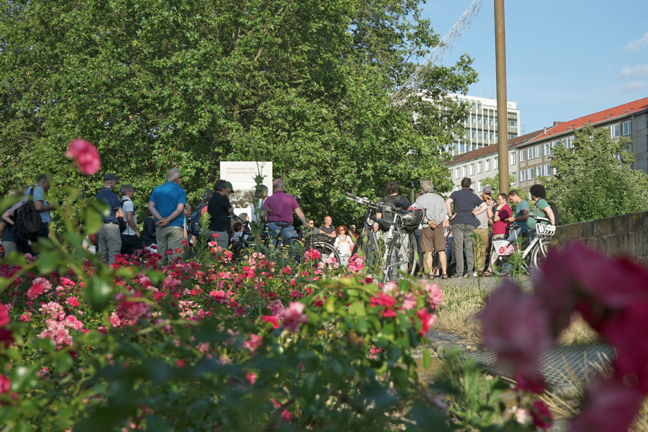 Blumen im Vordergrund; im Hintergrund haben sich Menschen bei einer Mobilen Bürgerversammlung versammelt., Bild © Leopold Werner / Stadt Nürnberg