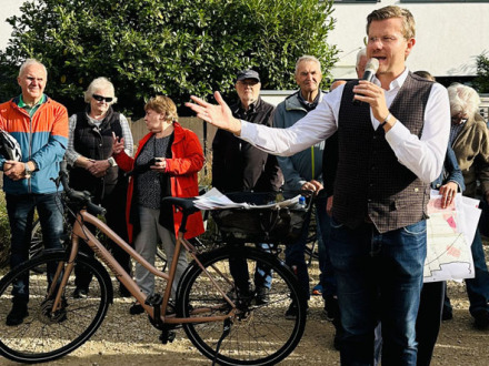 Bild © Sabine Hieronymus / Stadt Nürnberg Foto: Der Ober·bürgermeister Marcus König spricht in ein Mikrofon. Links neben dem Ober·bürgermeister steht ein Fahr·rad. Im Hintergrund stehen viele Menschen und hören zu., Bild © Sabine Hieronymus / Stadt Nürnberg