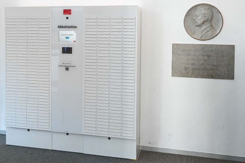 © Christine Dierenbach Die neue Abholstation für Ausweise in der Stadtbibliothek Zentrum ähnelt einer Packstation. Ein Display und ein Scanner in der Mitte regelt die Ausgabe. Links und rechts davon befinden sich Schubfächer für die Ausweise, deren Türen sich bei Nutzung öffnen. © Christine Dierenbach