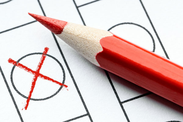 Symboldbild für Wahlen: Ein roter Buntstift und ein rotes Kreuz in einem Feld.