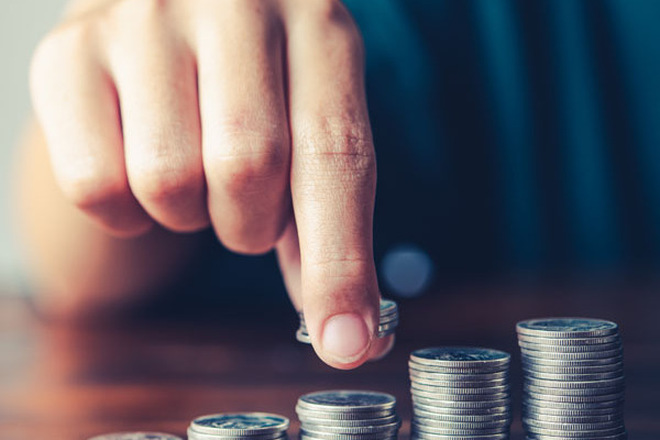 Symbolbild für Finanzen: Eine Hand stapelt Münzen in einer Reihe auf.