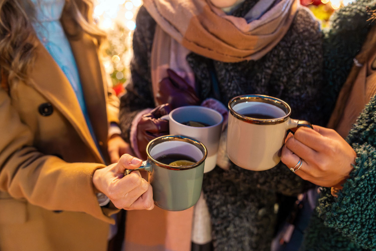 Drei Frauen stoßen mit Glühweintassen an. Fokus auf die Hände mit den Tassen., Bild © Giuseppe Lombardo / AdobeStock