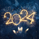 Die Zahl 2024 vor blauem Nachthimmel im sprühenden Goldgelb mit Funkenflug von Wunderkerzen.