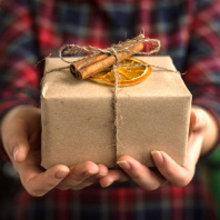 Eine Frau hält ein schön verpacktes Weihnachtsgeschenk in den Händen.