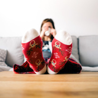 Frau mit Weihnachtssocken auf dem Sofa sitzend.