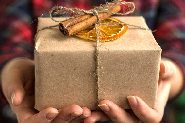 Eine Frau hält ein schön verpacktes Weihnachtsgeschenk in den Händen.