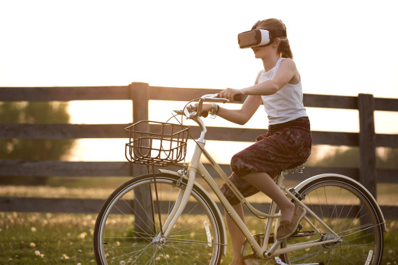 Mädchen auf einem Fahrrad, das eine VR-Brille aufhat.
