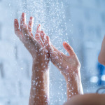 Eine Frau steht unter einer laufenden Dusche.