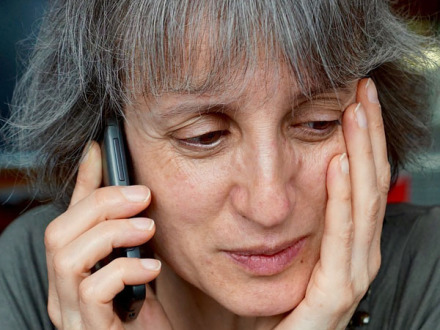 Das Bild zeigt: Eine besorgte Frau telefoniert.